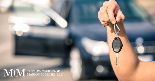 person holding car key with car in background